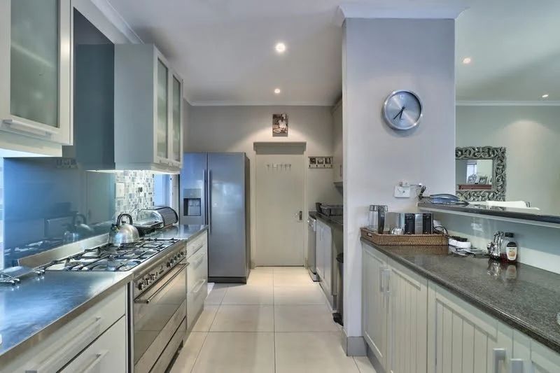 Spacious open-plan kitchen and dining area in Cape Town Beach Villa, featuring sleek cabinetry, a modern breakfast bar, and seamless flow into the living space for effortless entertaining.